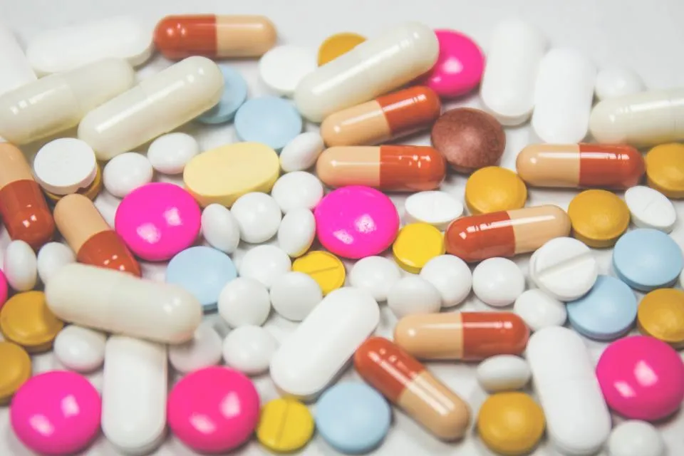Assorted tablets and capsules spread on a white surface